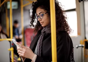 Landscape image of female wearing glasses whilst on public transport 