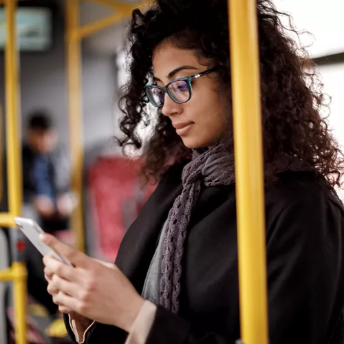 Landscape image of female wearing glasses whilst on public transport 