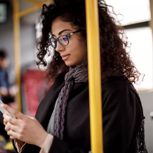 Landscape image of female wearing glasses whilst on public transport 