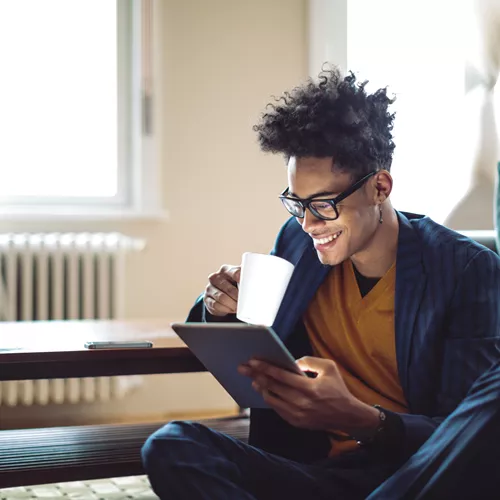 Landscape image of a male using a tablet whilst wearing glasses