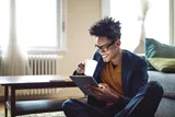 Landscape image of a male using a tablet whilst wearing glasses