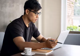 Landscape image of a male wearing glasses whilst working