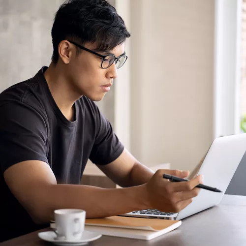 Landscape image of a male wearing glasses whilst working