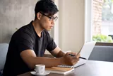 Landscape image of a male wearing glasses whilst working