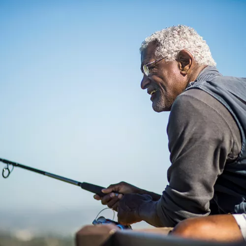 Uomo anziano che indossa gli occhiali mentre pesca all&#39;aperto
