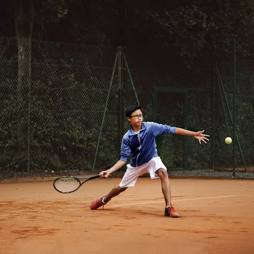 Uomo che indossa lenti sportive speciali HOYA mentre gioca a tennis