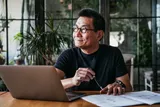 Man with blue light glasses working at a laptop