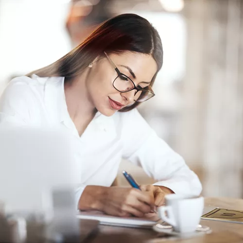 Donna con i capelli lunghi e gli occhiali che scrive qualcosa