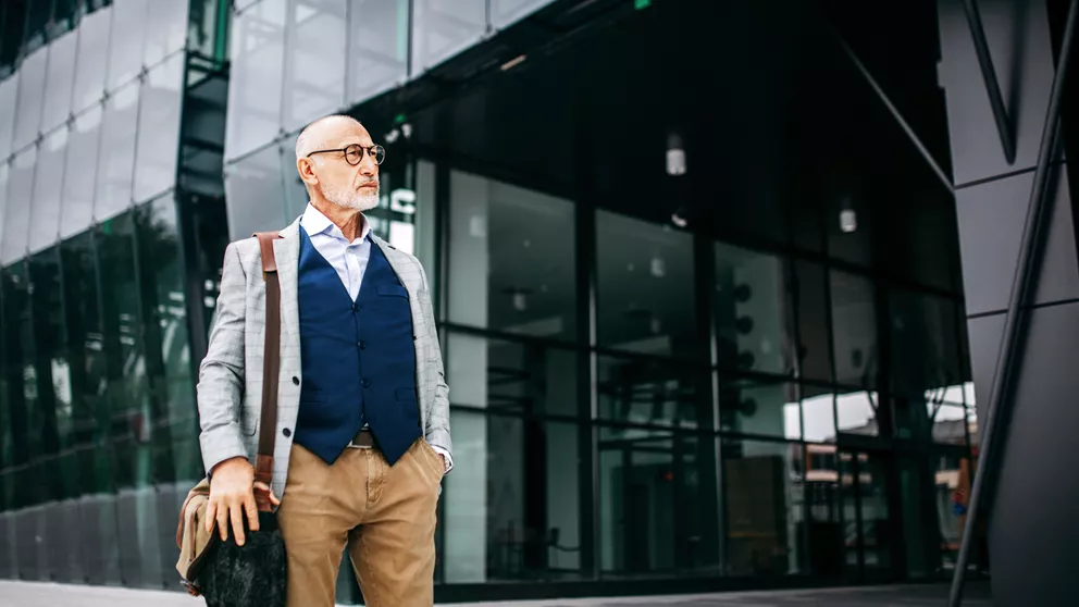 Older man wearing glasses standing in front of building
