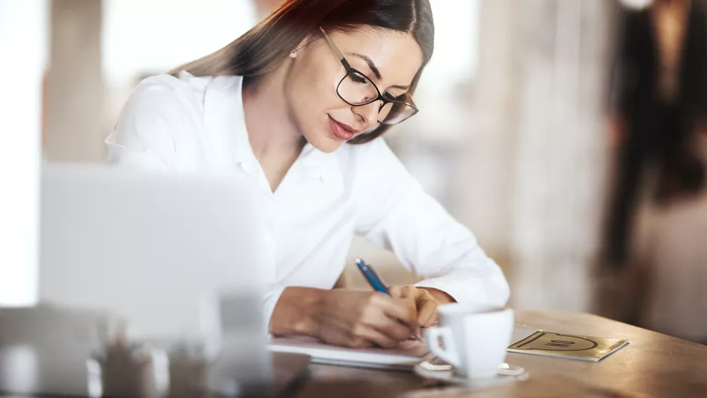 Woman with glasses writing on paper