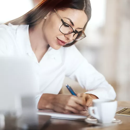 Woman with glasses writing on paper