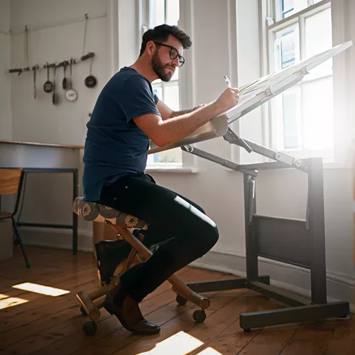 Man working on drafting table while wearing occupational glasses