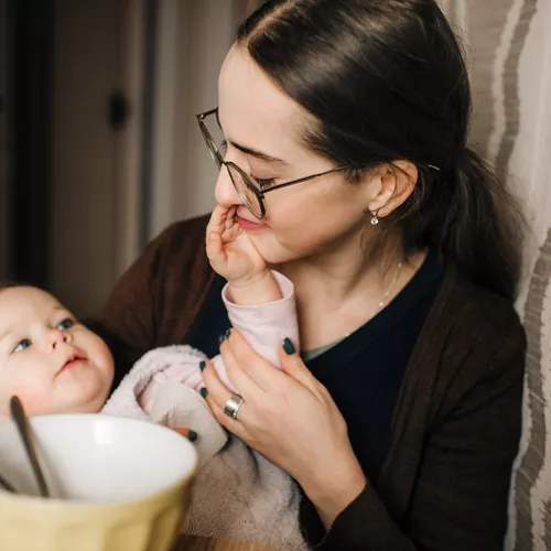 Donna che indossa lenti antibatteriche HOYA Hi-Vision mentre gioca con un bambino