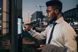 Man wearing glasses and a tie rings doorbell at night time