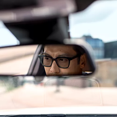 Man in the rearview mirror of a car while wearing driving glasses