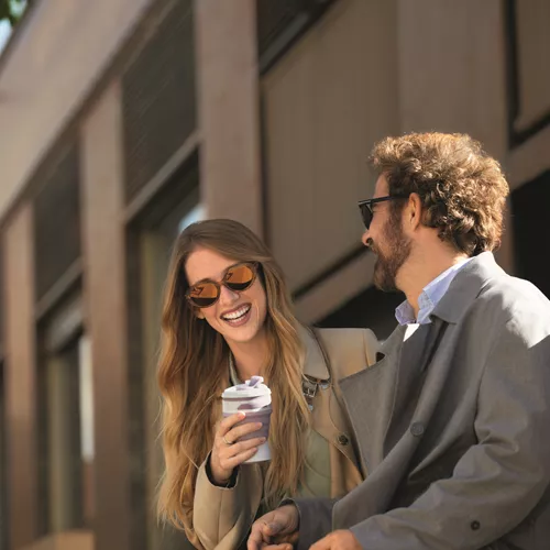 Two people drinking coffee outside while wearing sunglasses