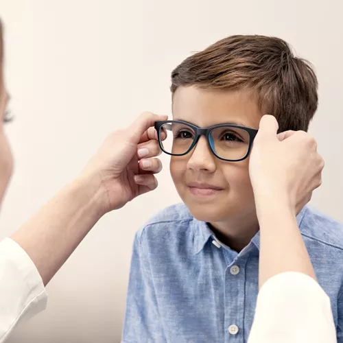 Optician helping boy with glasses