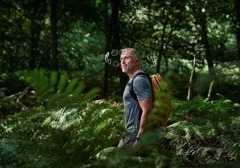 Man with backpack walking in forest, a halo of lenses around his head