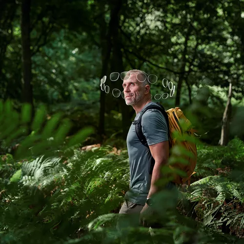 Un homme avec un sac à dos marchant dans la forêt, un halo de lentilles autour de sa tête