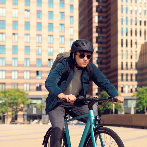 Un homme fait du VTT en ville, portant un casque et des lunettes de soleil HOYA Sensity Fast