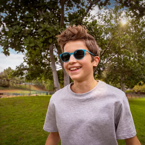 Boy in grey t-shirt standing outside while wearing HOYA MiYOSMART glasses