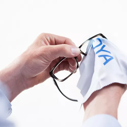 HOYA Optiker reinigt Brillen mit einem weißen HOYA-Tuch