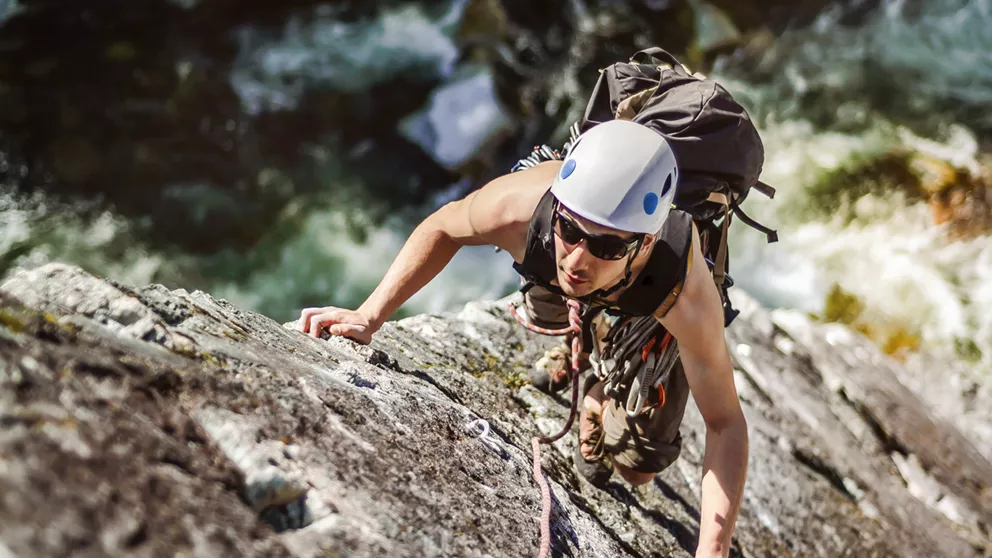Mann mit HOYA-Sonnenbrille mit speziellen Sportgläsern beim Bergsteigen