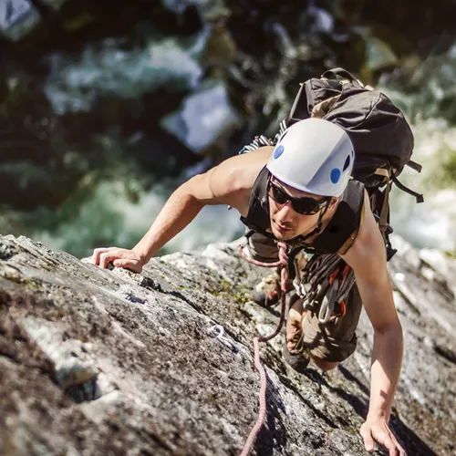Man with HOYA sunglasses featuring special sportive lenses climbing a mountain