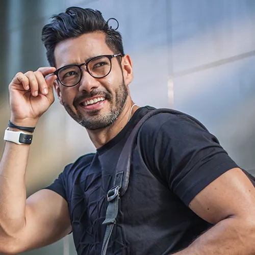 Homme souriant en arrière tout en ajustant ses lunettes