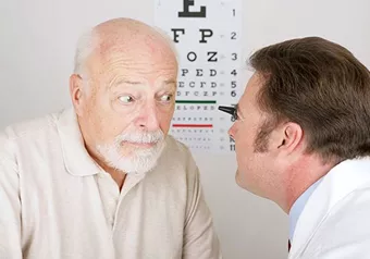Hoya Vision cataracts optician examining an elderly man's eyes