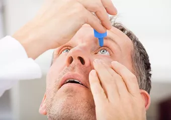 Male using eye drops to combat dry eye syndrome