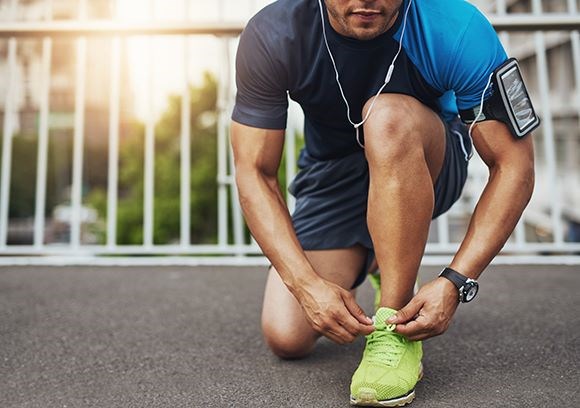 Male tying his running shoe laces