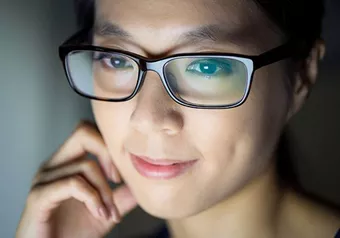 Woman in front of a screen wearing eyeglasses with Hoya Vision lenses