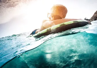 Male floating on water wearing glasses with Hoya Vision lenses protecting from UV rays