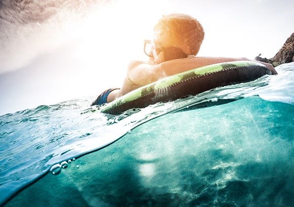 Male floating on water wearing glasses with Hoya Vision lenses protecting from UV rays