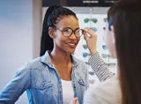 Woman in an optician trying on eyeglasses with Hoya Vision lenses