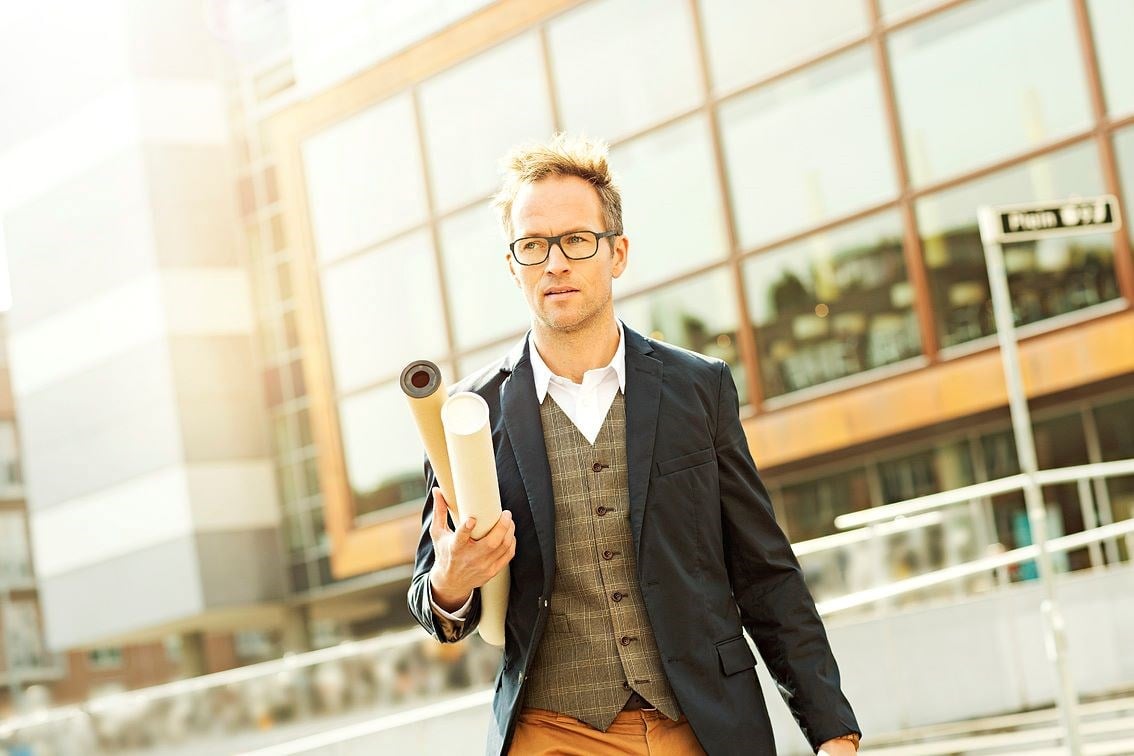 Male carrying scrolls outdoors wearing a pair of eyeglasses with Hoya Vision UV treated lenses