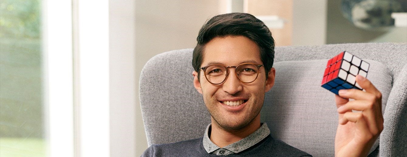 Male wearing eye glasses with Hoya Vision lenses holding a rubik's cube