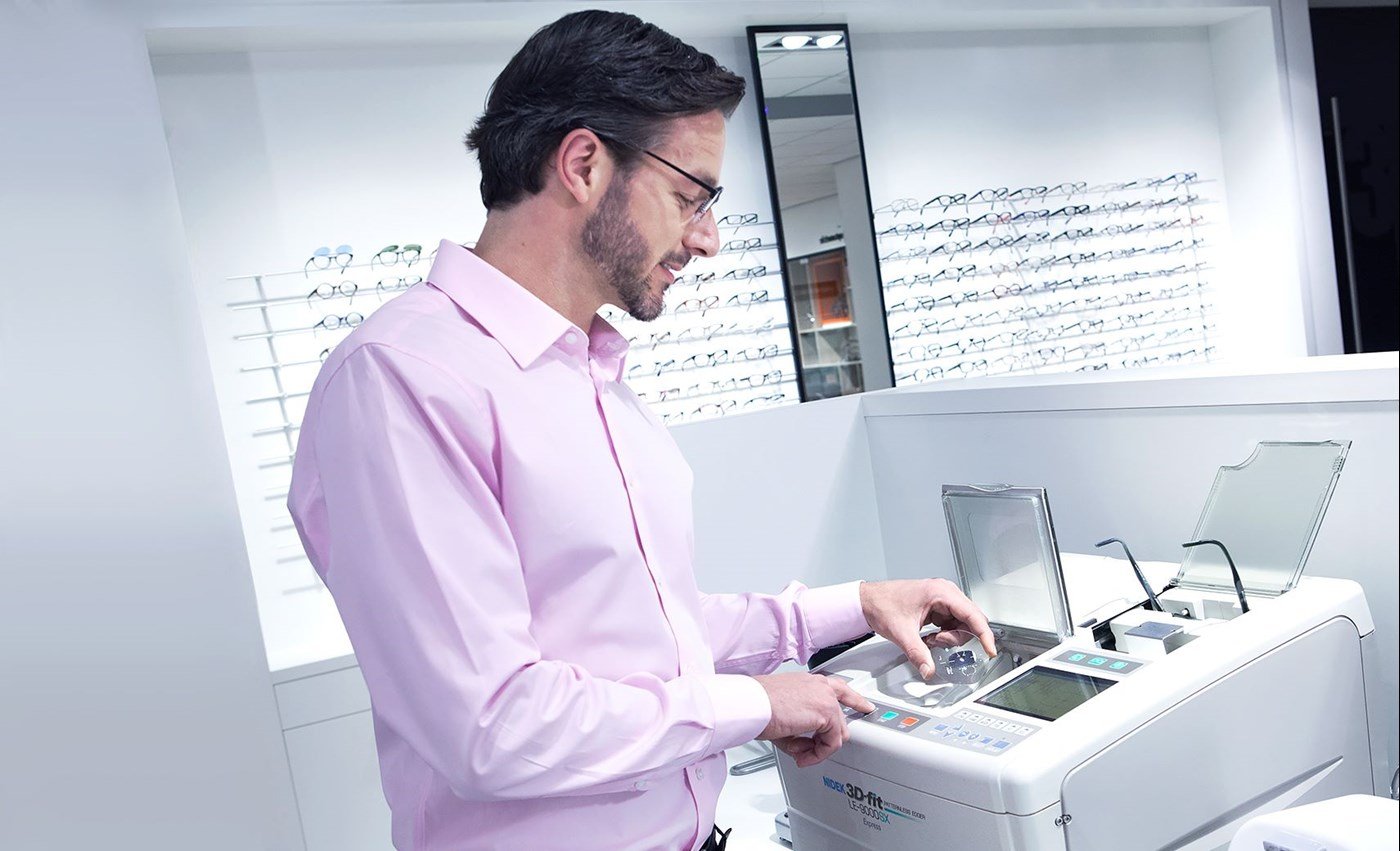 Male Hoya Vision optician in a pink shirt looking into a machine