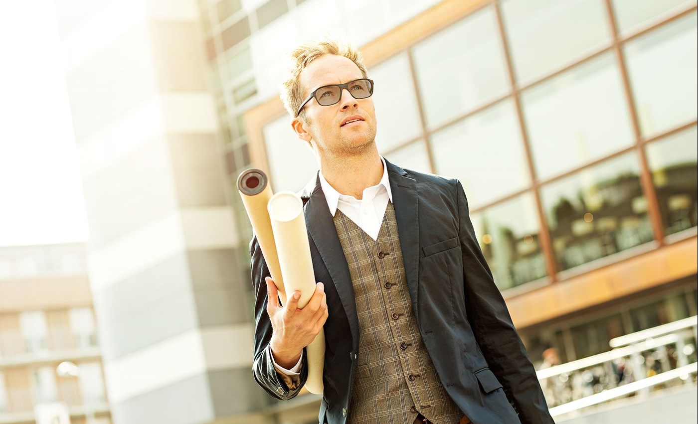 Male outdoors wearing eyeglasses with Hoya Vision photochromic lenses carrying scrolls