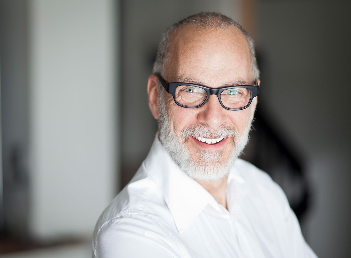 Man in white shirt smiling wearing Hoya Vision eyeglass lenses