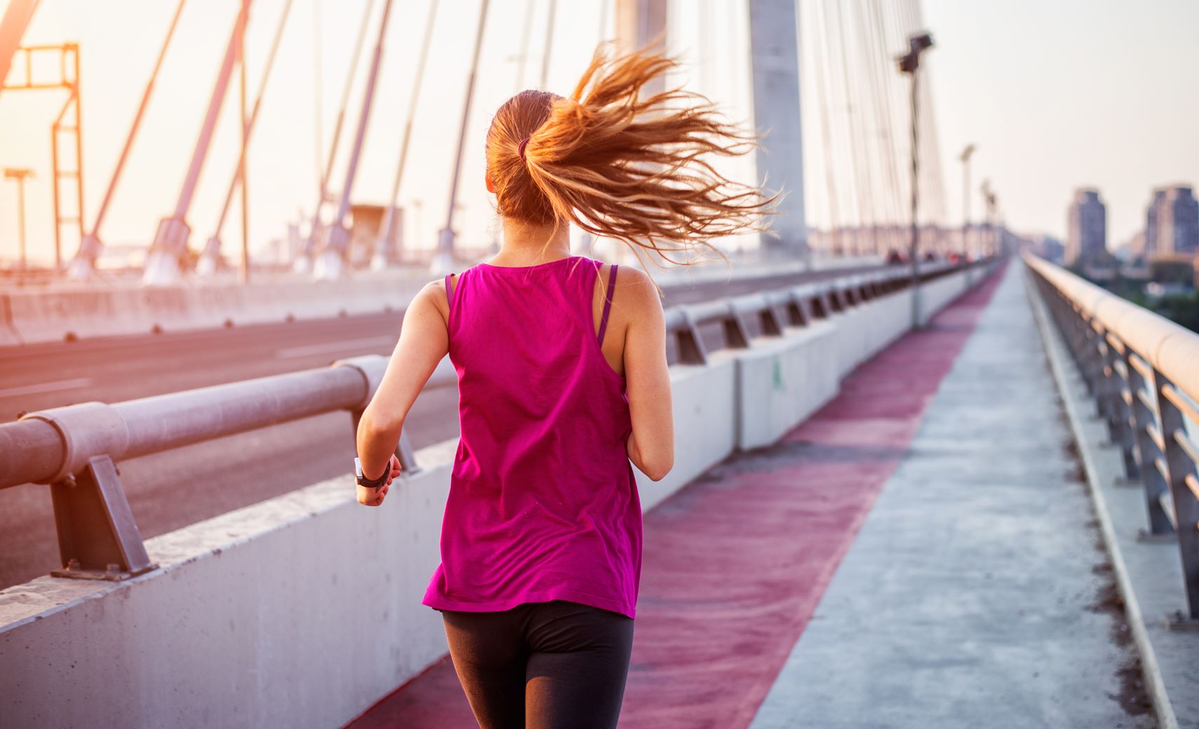Woman in pink top running along a bridge