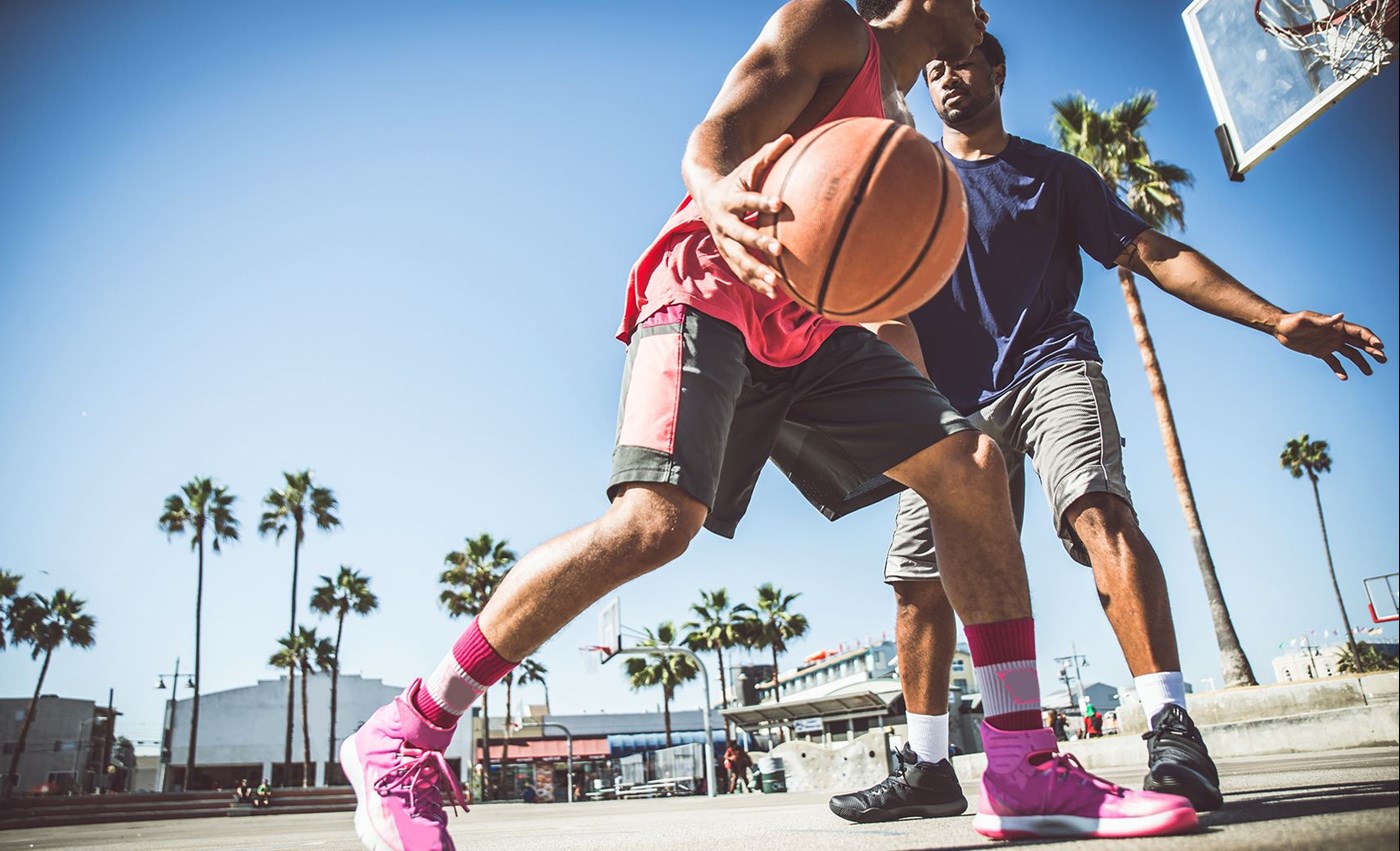 Two males playing basketball outside