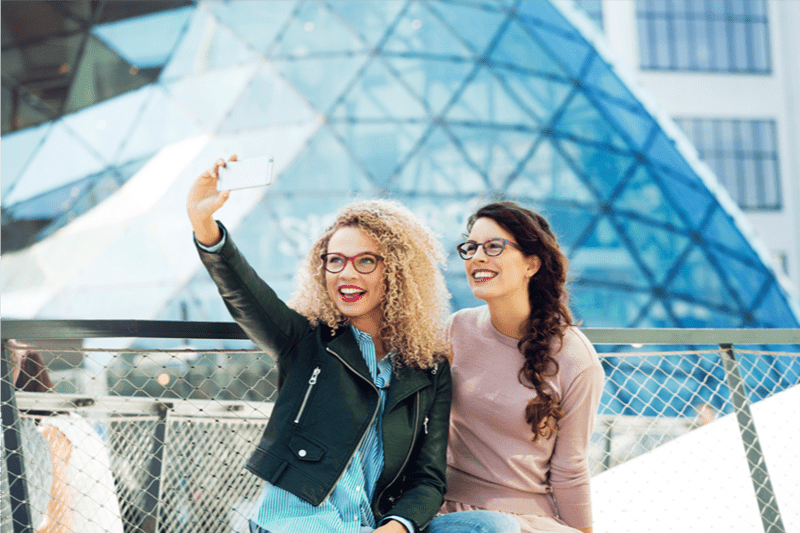 Two females outdoors wearing eyeglasses with Hoya Vision lenses taking a selfie