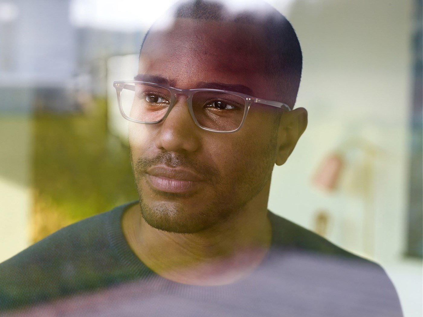Male wearing eyeglasses with Hoya Vision lenses looking out a window