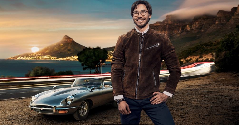 Male wearing eyeglasses stood infront of vintage car at tunnel enterance