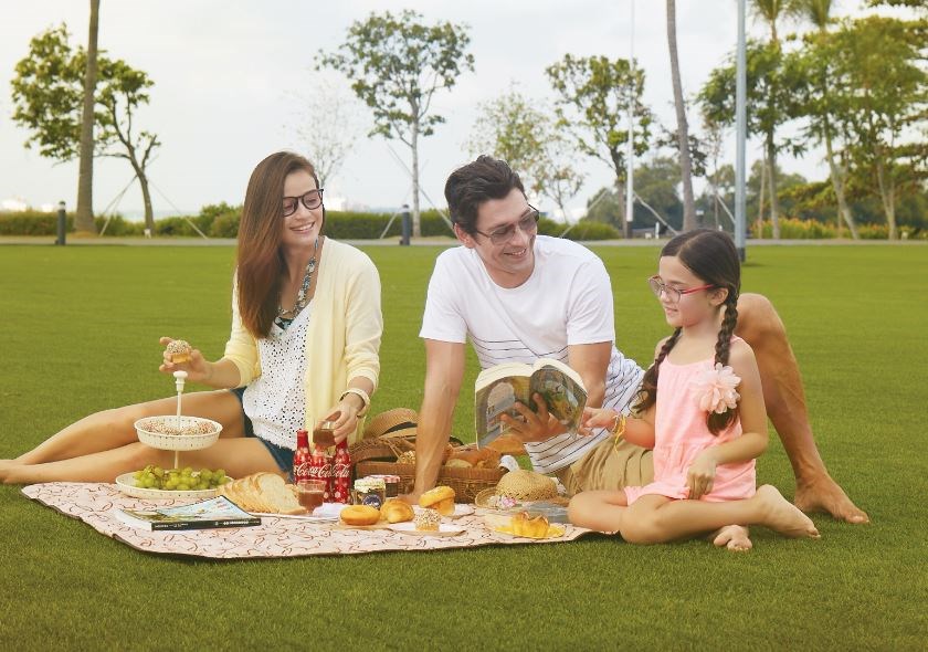 Parents and daughter all wearing eyeglasses having a picnic outdoors
