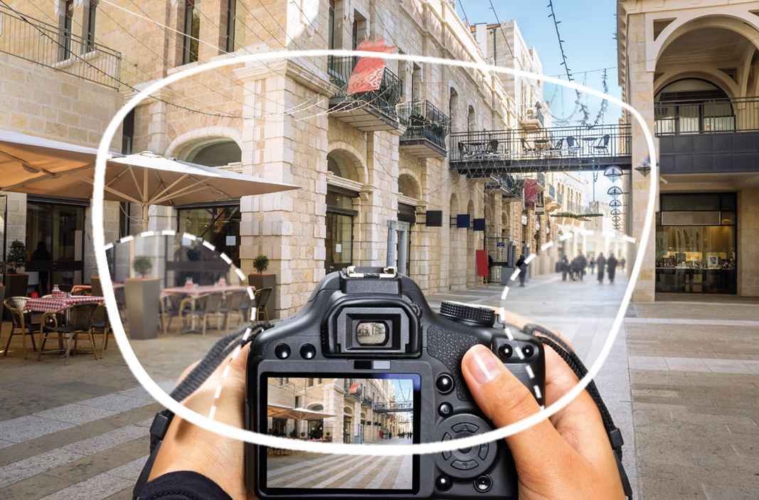 User holding camera taking image of street through an eyeglass lens