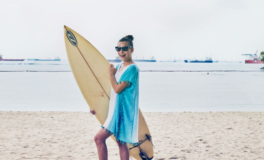 Female surfer in blue beach coverup and sunglasses
