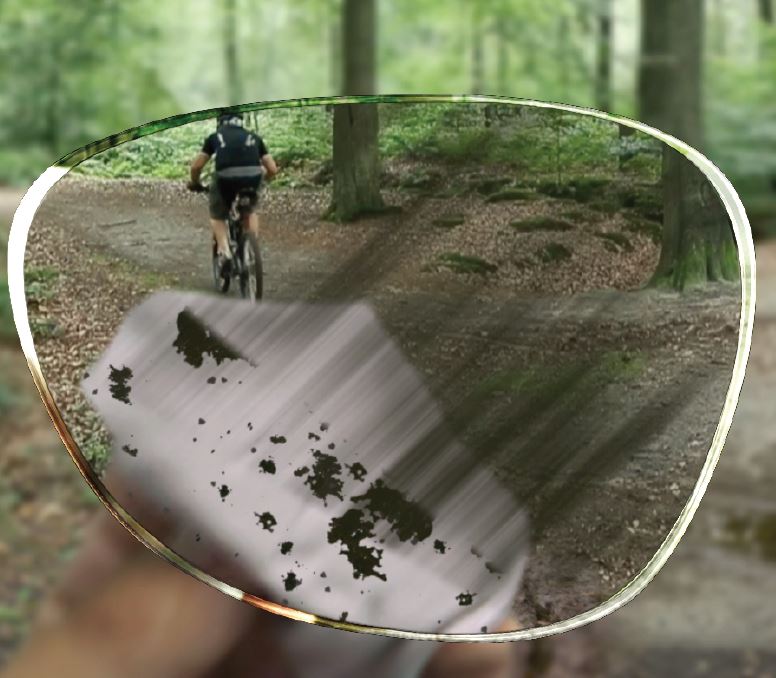 Dirty lens being wiped clean while on mountain bike track